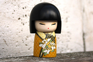 Une poupée en bois, habillé avec un kimono jaune, qui est peint